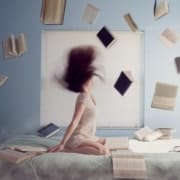 Eerste hulp bij overprikkeling - vrouw op bed met boeken
